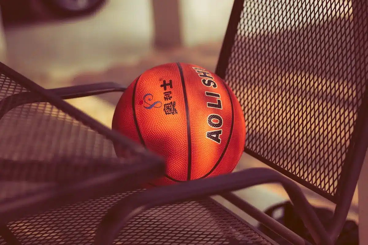 Folded roster sheets and a basketball on a team bench illustrating roster decisions