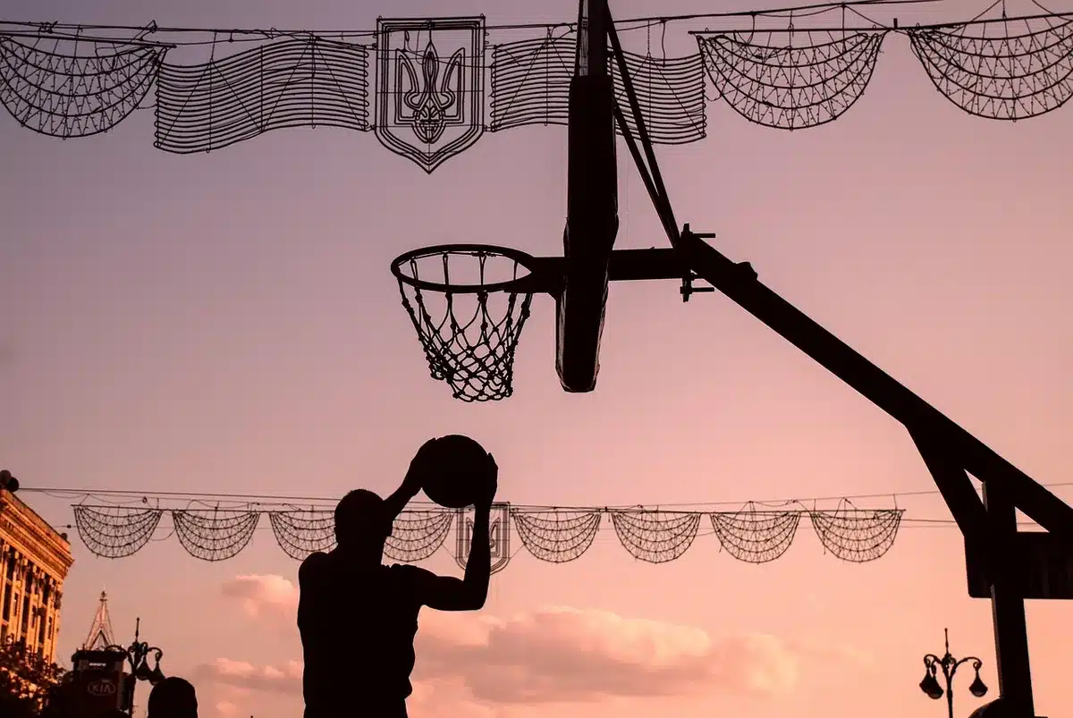 Silhouetted players exchanging a handshake on a basketball bench