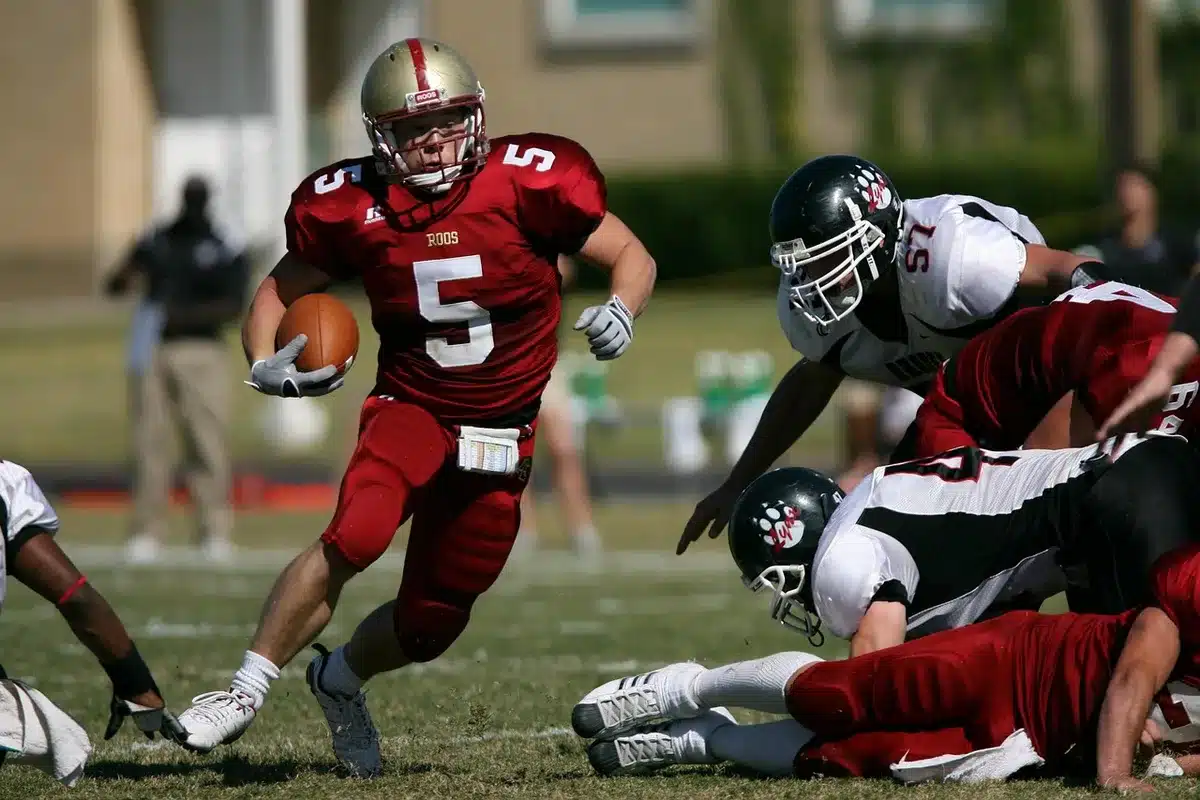 College football sideline with helmets, clipboard and cleats on bench