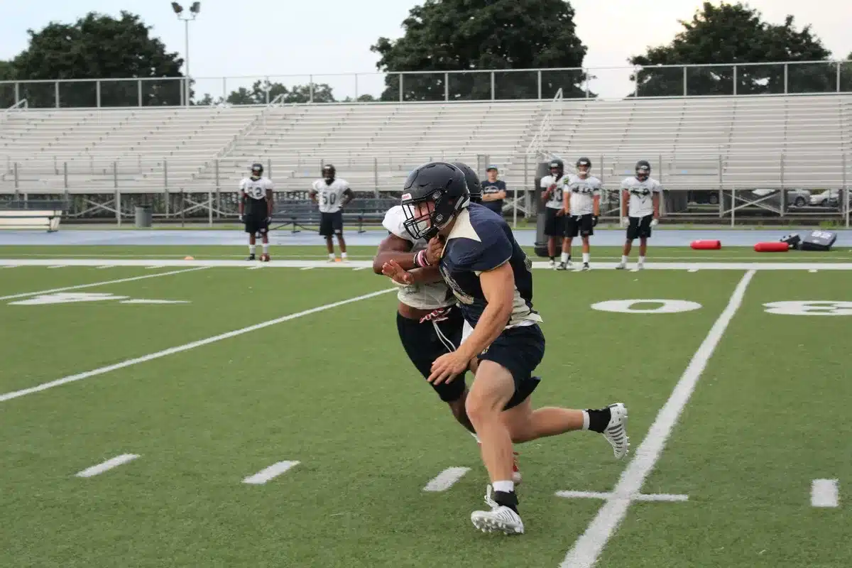 Defensive linemen engaging in a practice drill at the line of scrimmage