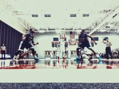 Two anonymous players fighting for a rebound near the rim on an indoor court