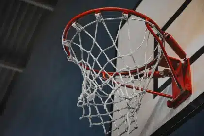 Silhouette of a player diving for an offensive rebound near the rim in an indoor court