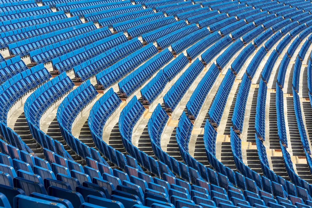 Fans on an open concourse overlooking a stadium bowl with many lower seats visible
