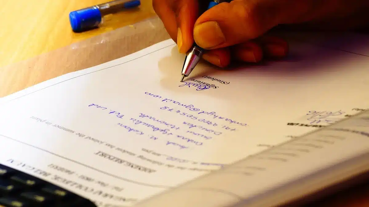 Close-up of hands signing a basketball contract on a clipboard