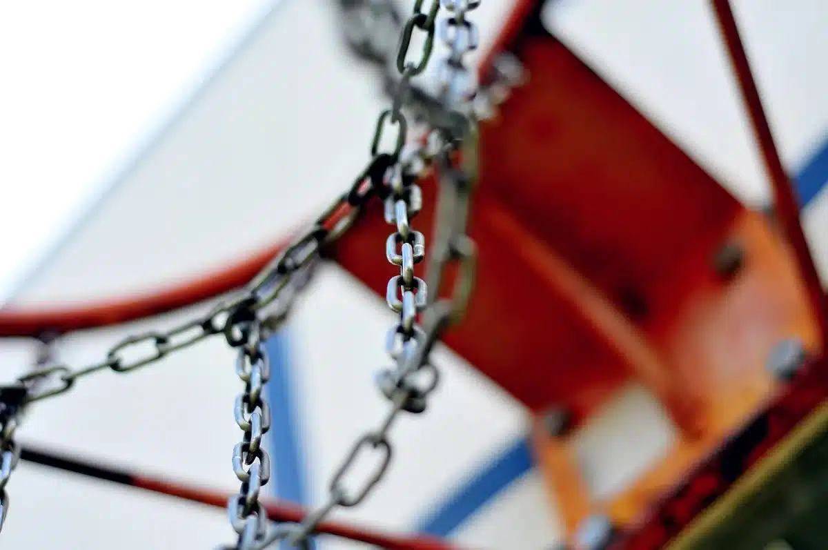 Two silhouetted basketball players boxing out for a rebound under the rim in an arena