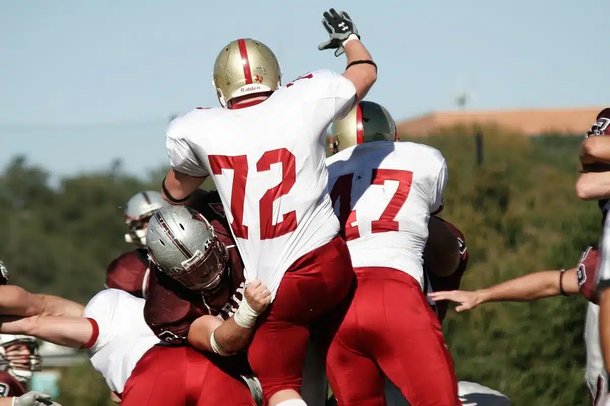 Anonymous offensive lineman working a blocking sled during practice on a sunny field